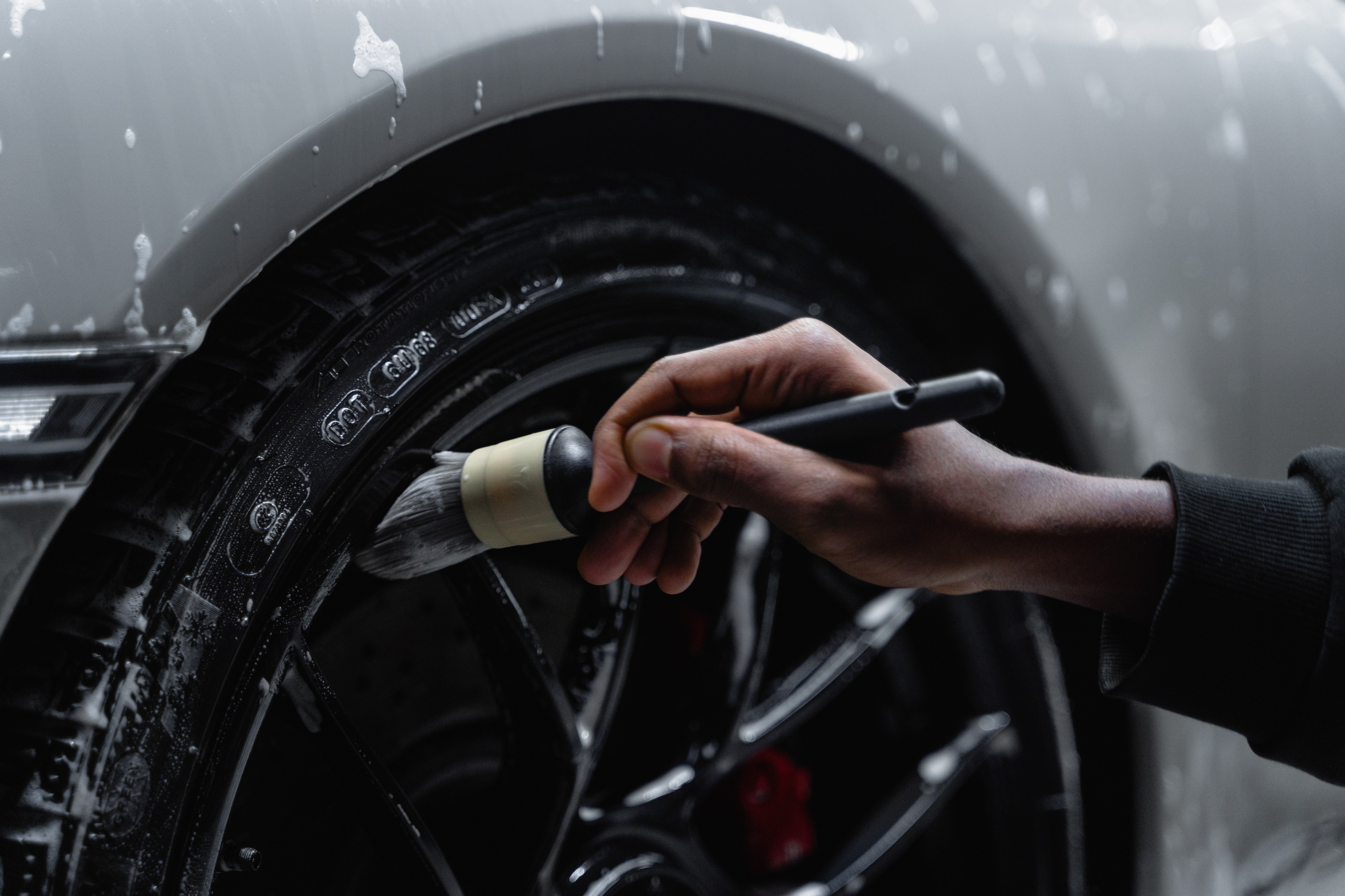 Detailer cleaning rims of a vehicle.